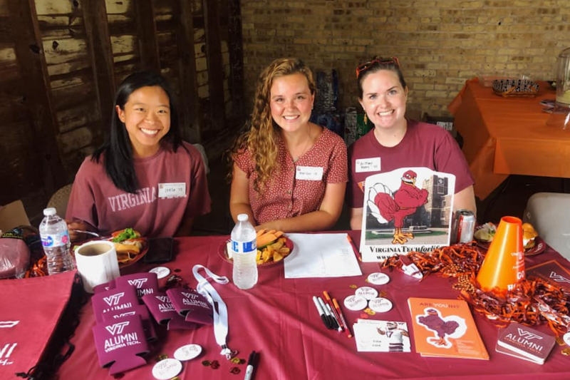 Members of the Chicago alumni chapter sit at a table with lots of Hokie swag