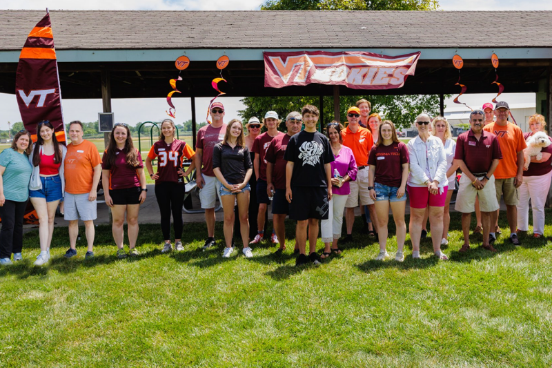 A large group of Southeast Michigan alumni chapter members pose for a photo outside with Virginia Tech decorations