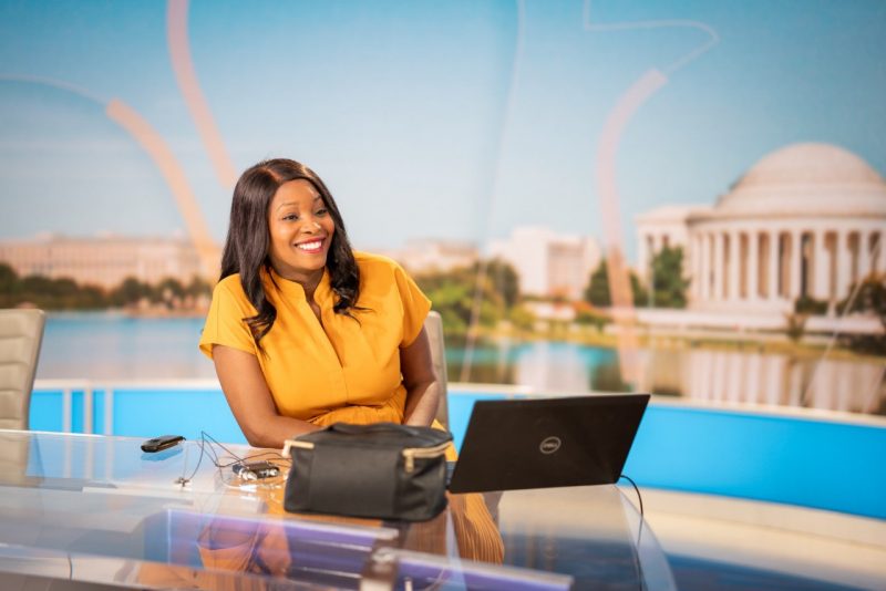 Female news anchor at news desk.